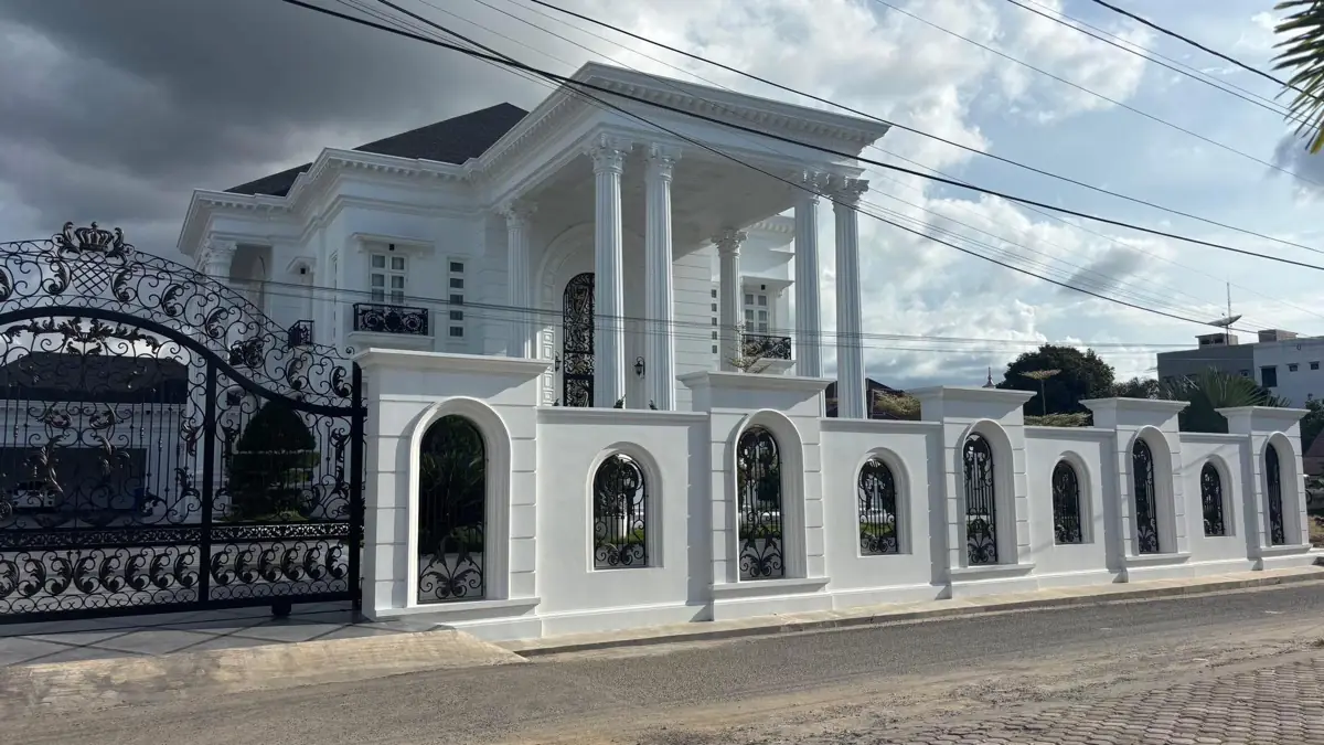 Detail pagar putih dengan bukaan lengkung dan teras di belakangnya.